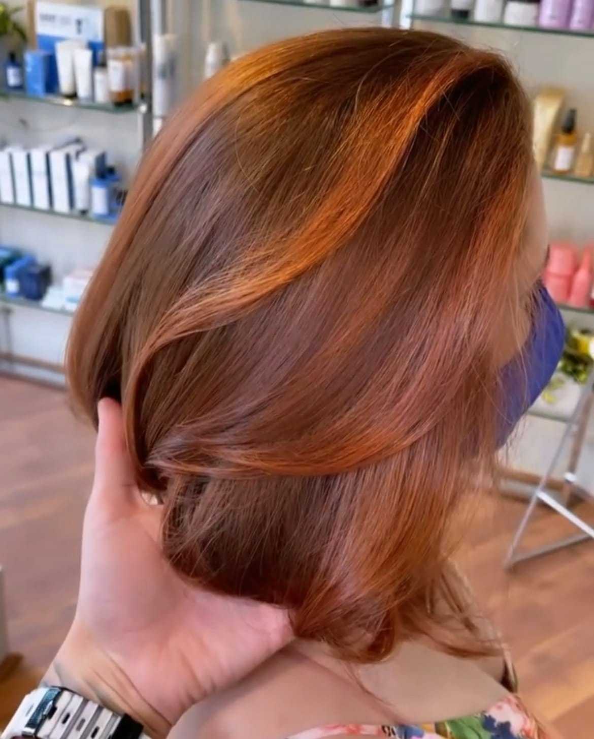 Woman’s freshly styled reddish-brown hair in a modern salon setting.